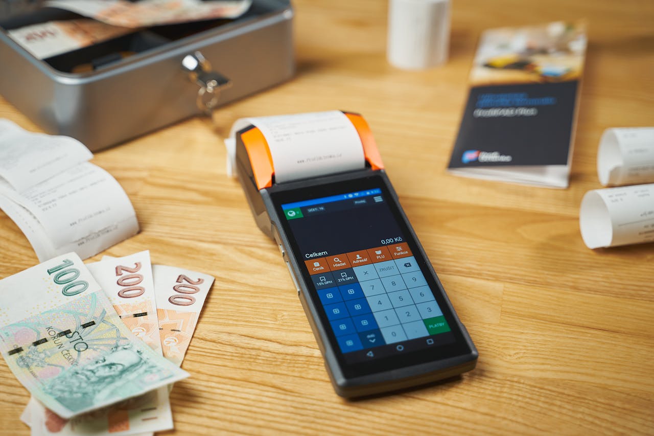 creative A modern digital payment terminal on a wooden desk with cash and receipts.