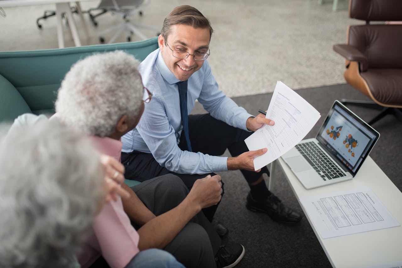 Services-01 Financial advisor discussing documents with senior clients in an office setting, showcasing a collaborative consulting session.